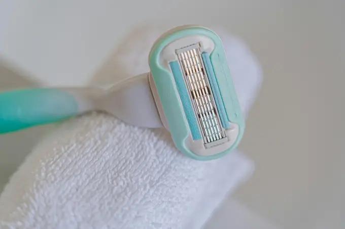 Close-up of a Gillette Venus disposable razor with turquoise detailing resting on a white towel