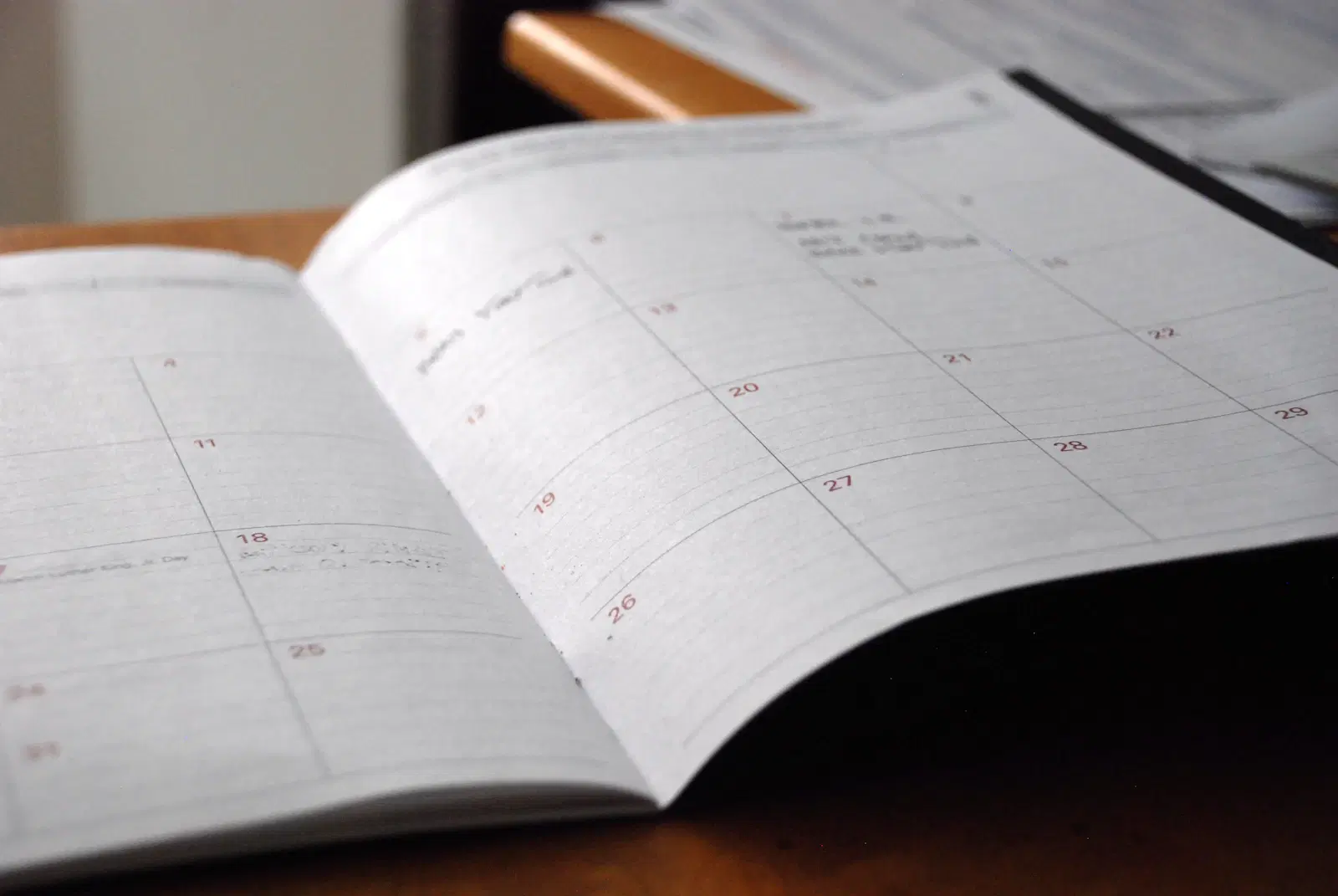 An open monthly planner lying on a wooden desk
