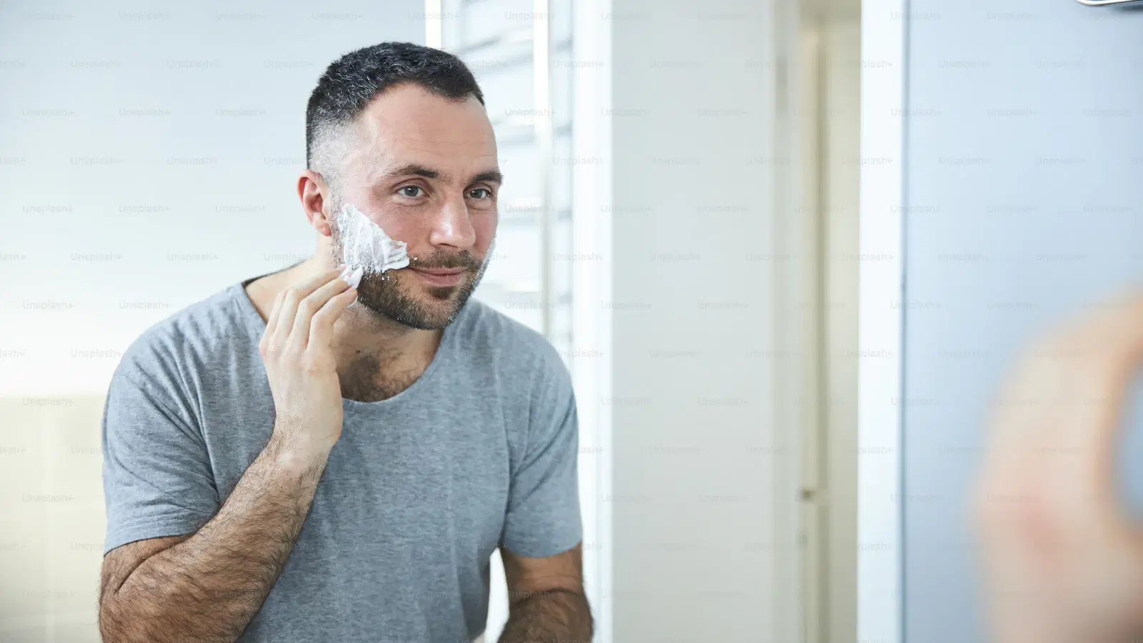 Philips Norelco OneBlade electric pubic trimmer being used for bikini-line grooming — dual-sided head, rounded guard, shower-safe design