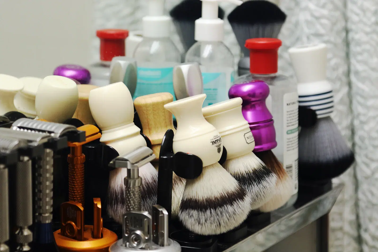 Shaving brushes, razors, and grooming products crowded on a bathroom counter