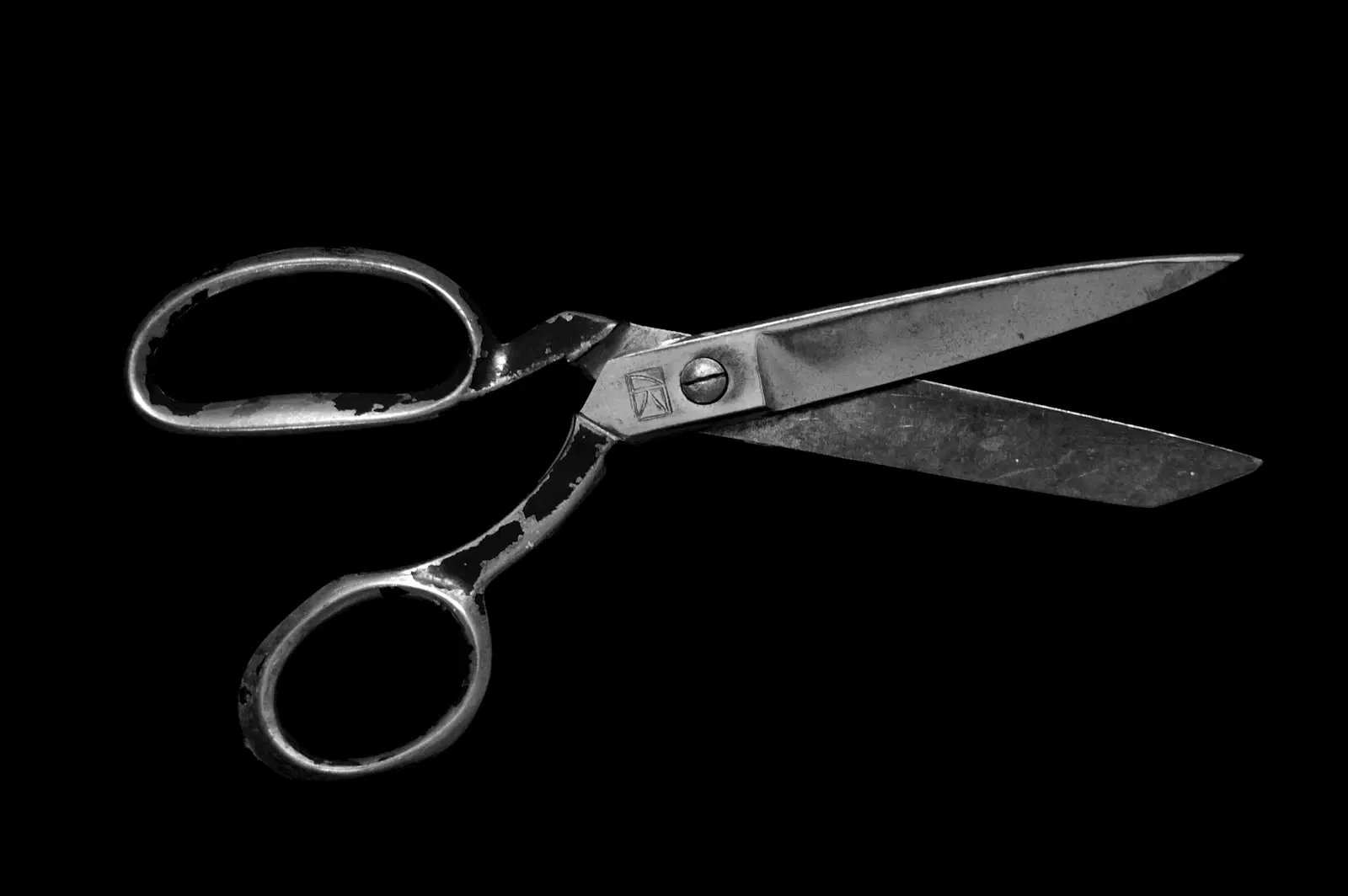 Pointed steel household scissors on a black background, the kind to keep away from your nose