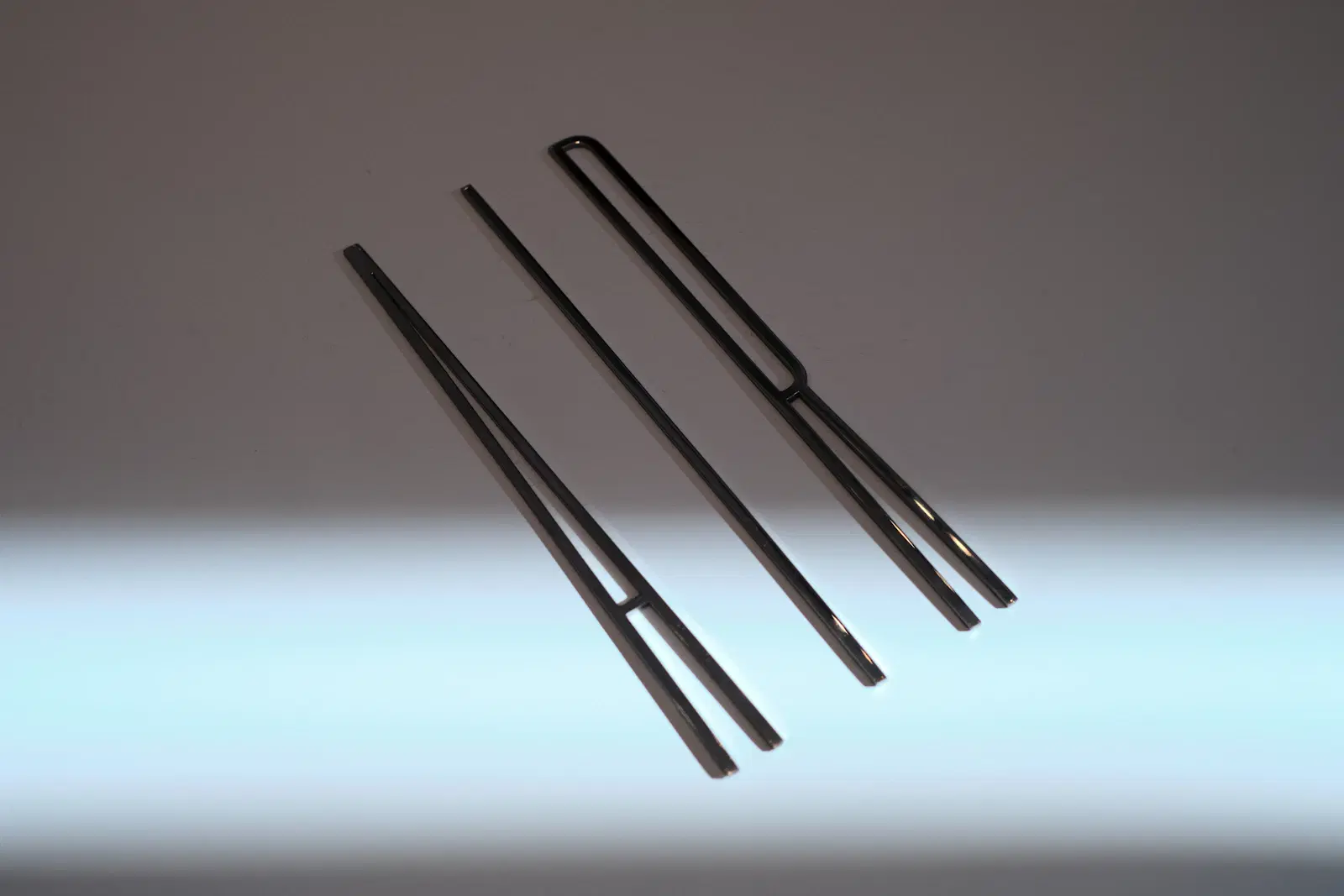 Three metal tweezers on a gray background