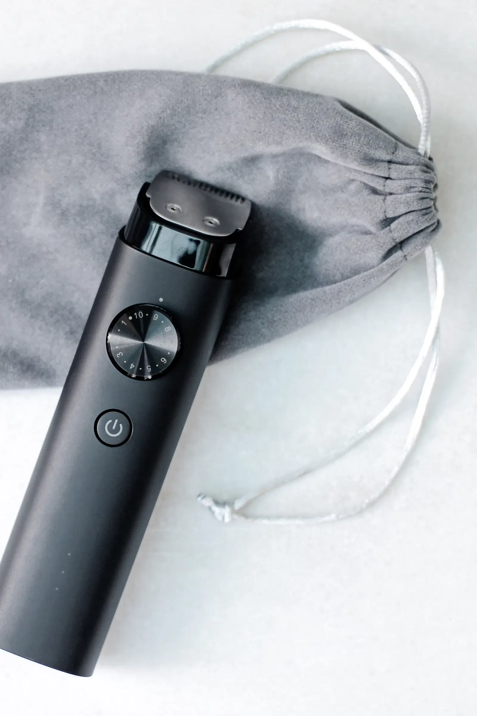 A black electric body trimmer resting on a gray drawstring pouch