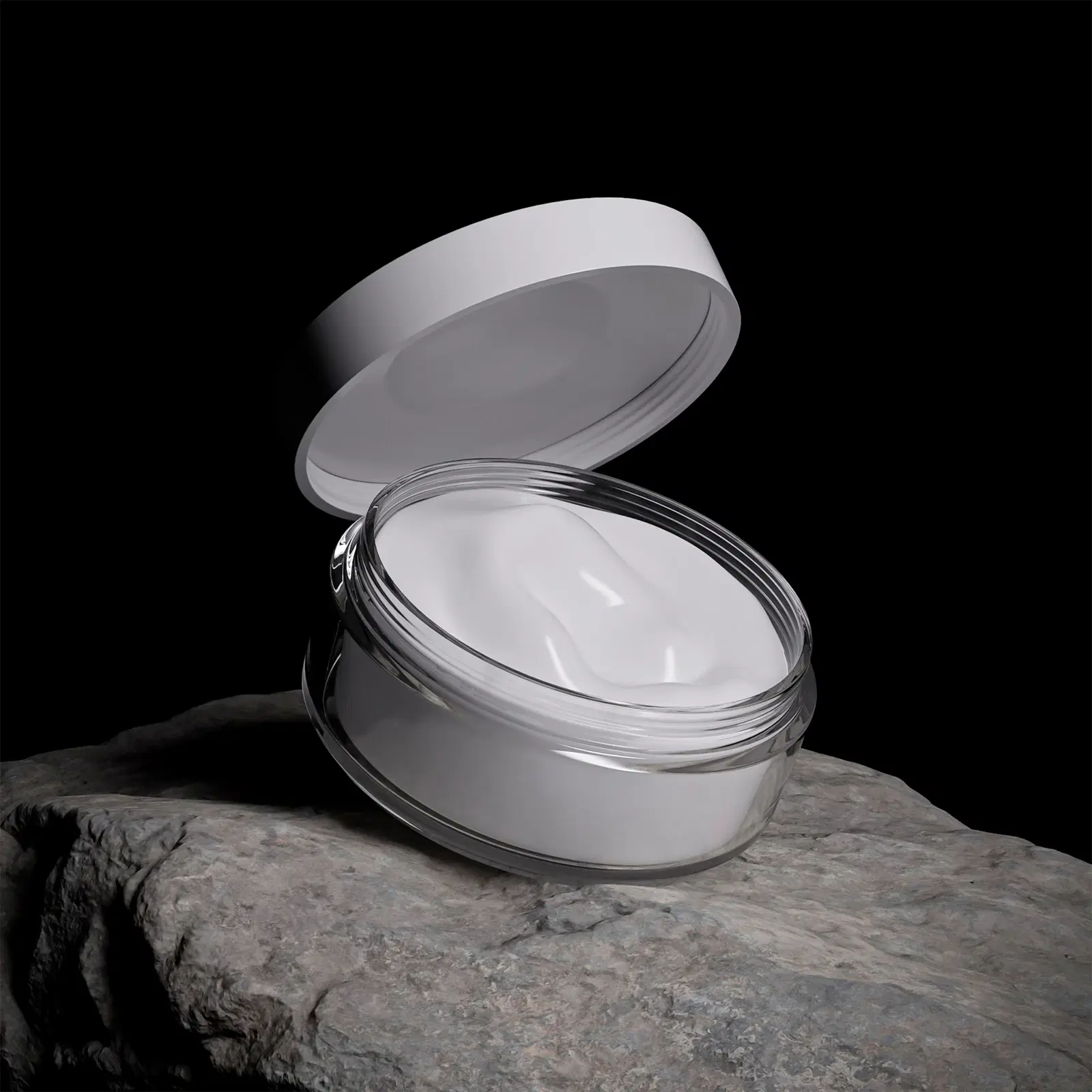 An open jar of white cream on a dark stone