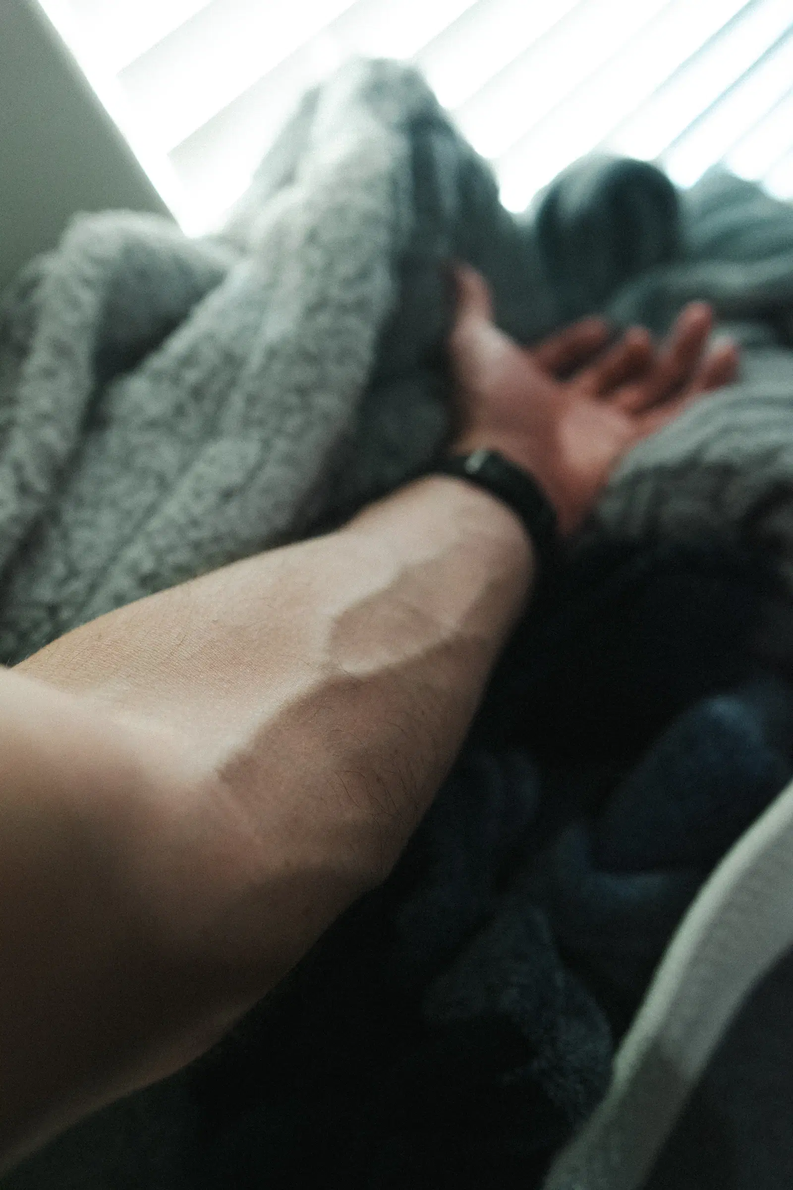 A man's forearm with natural arm hair and a black watch strap