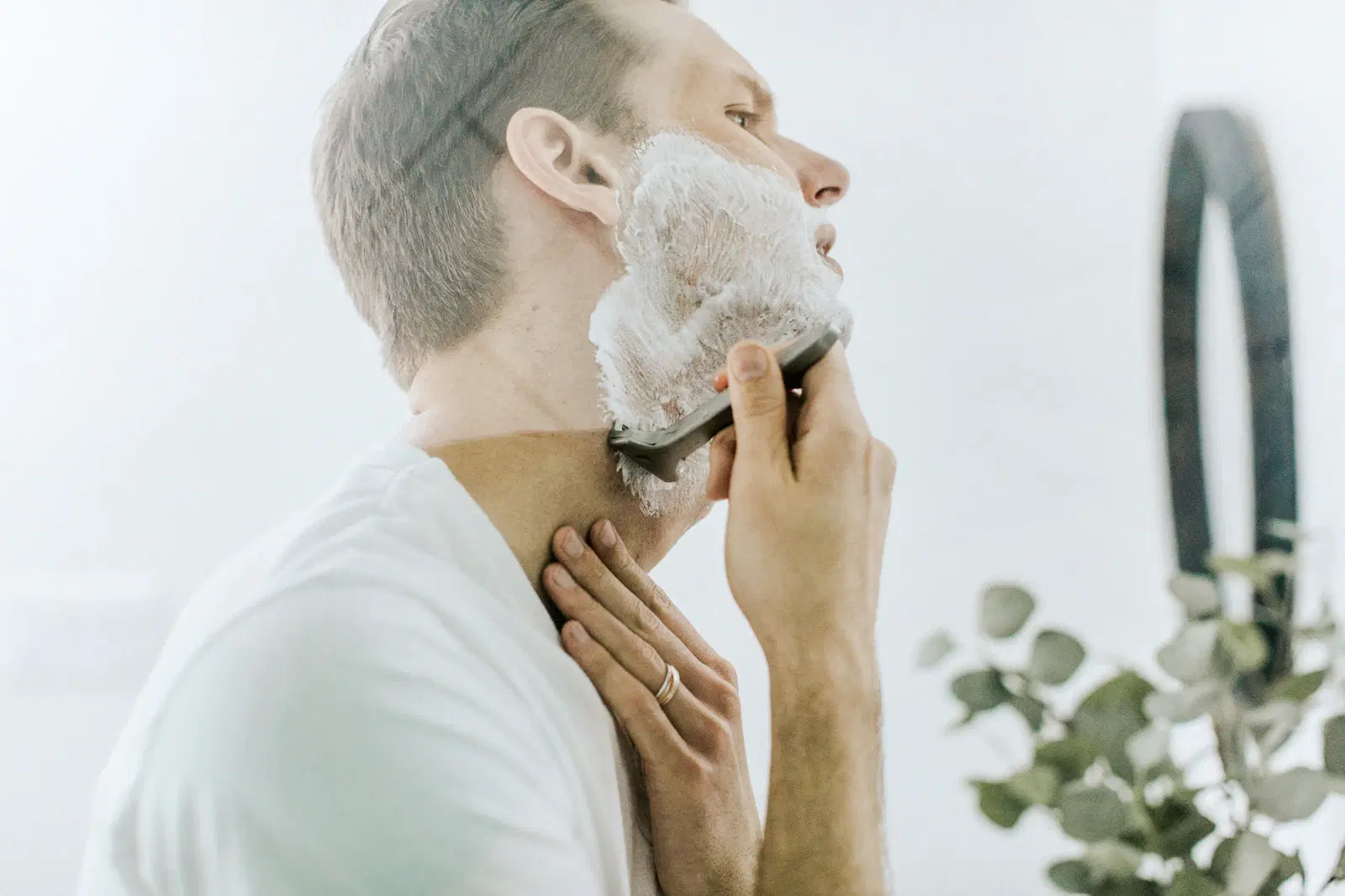 A man shaving his face with a razor and white shaving foam