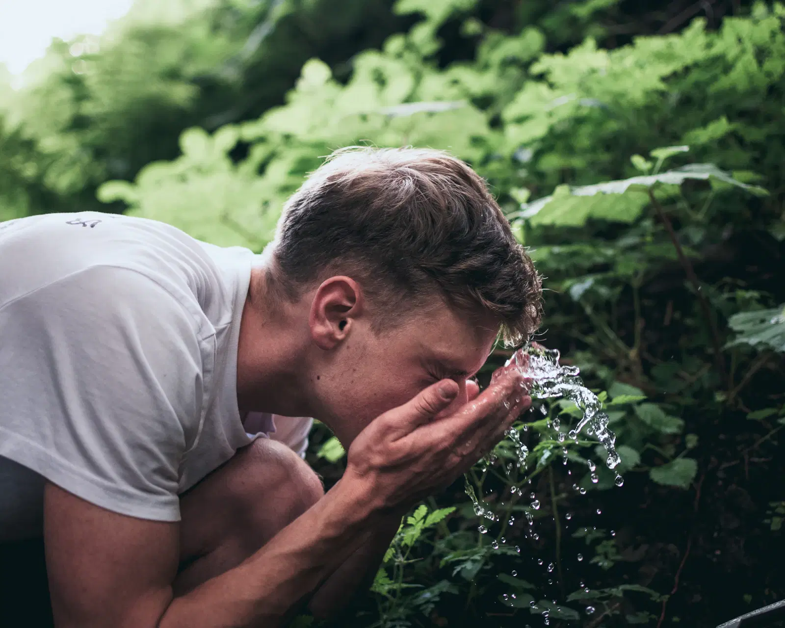 A man splashing water on his face outdoors