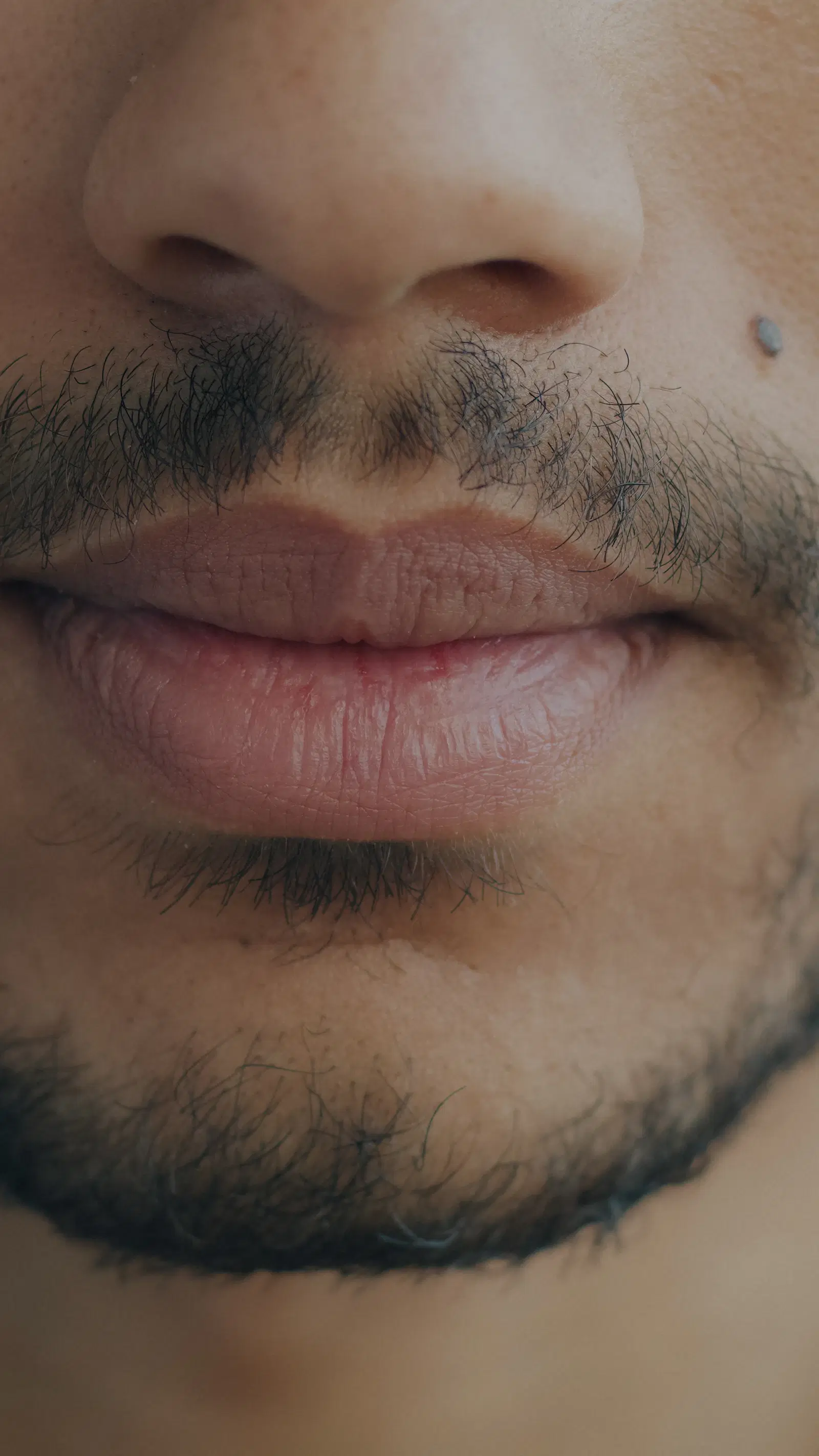 Close-up of a man's mouth and chin with short, even stubble