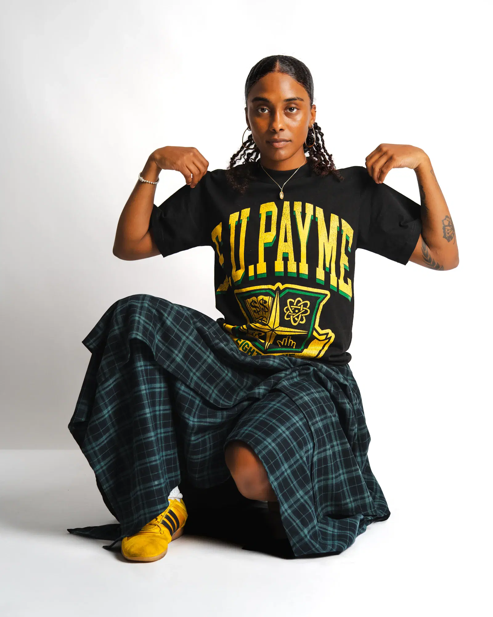 Black oversized graphic tee with a long green plaid skirt and yellow sneakers