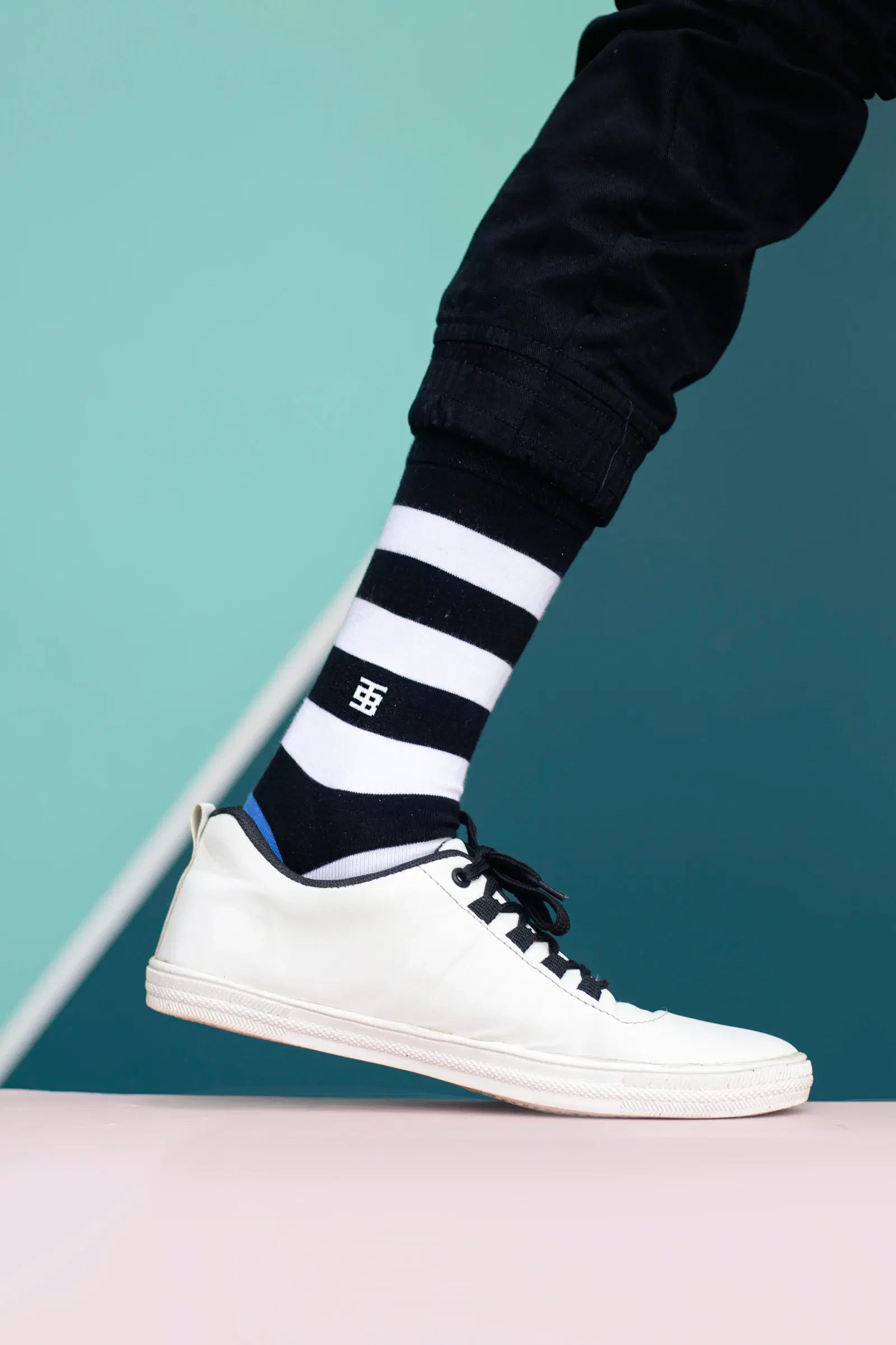 Black-and-white striped sock under black joggers with a white sneaker