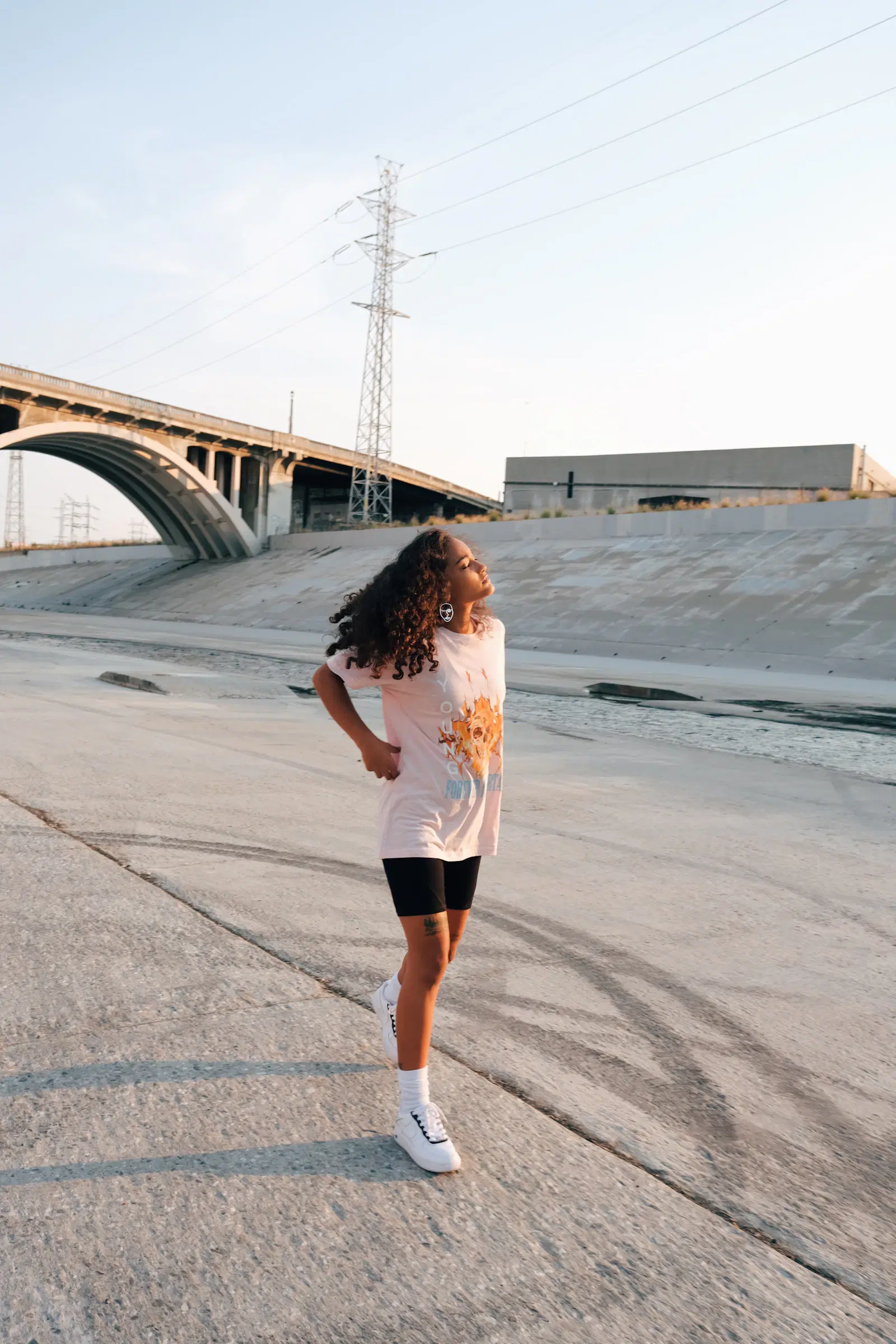 Black bike shorts worn under an oversized pale pink graphic tee, the same kind of shorts that go under a skirt
