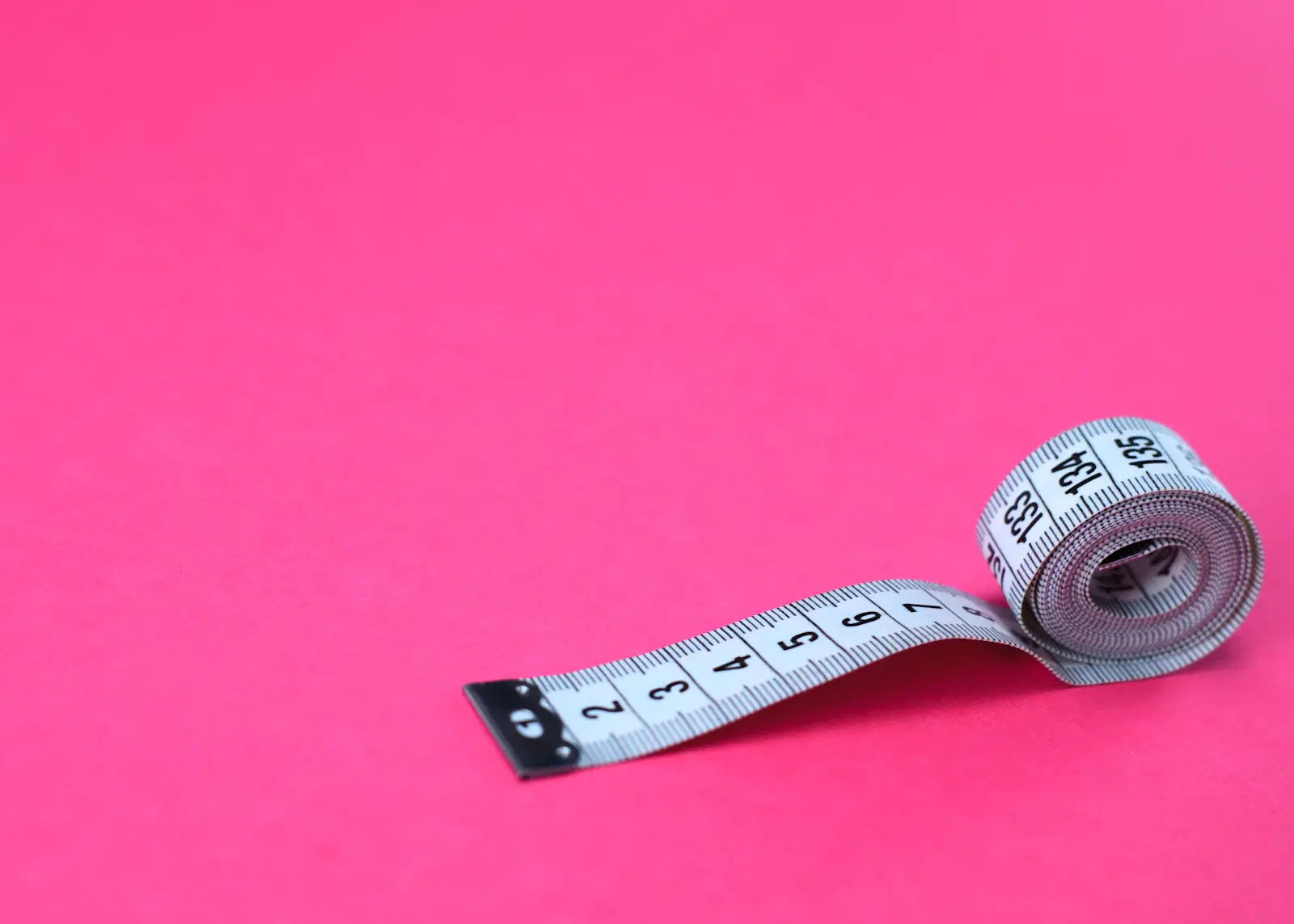 Soft sewing tape measure on a pink background for finding your skirt size