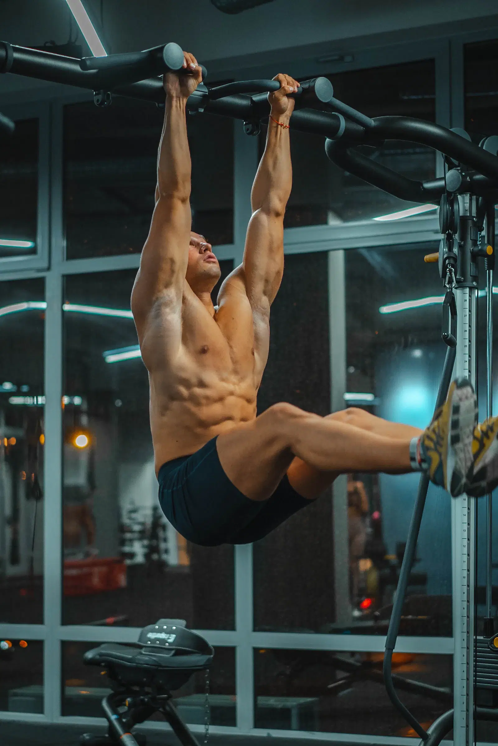 Man doing hanging knee raises on a pull-up bar to train his core for a smaller femboy waist