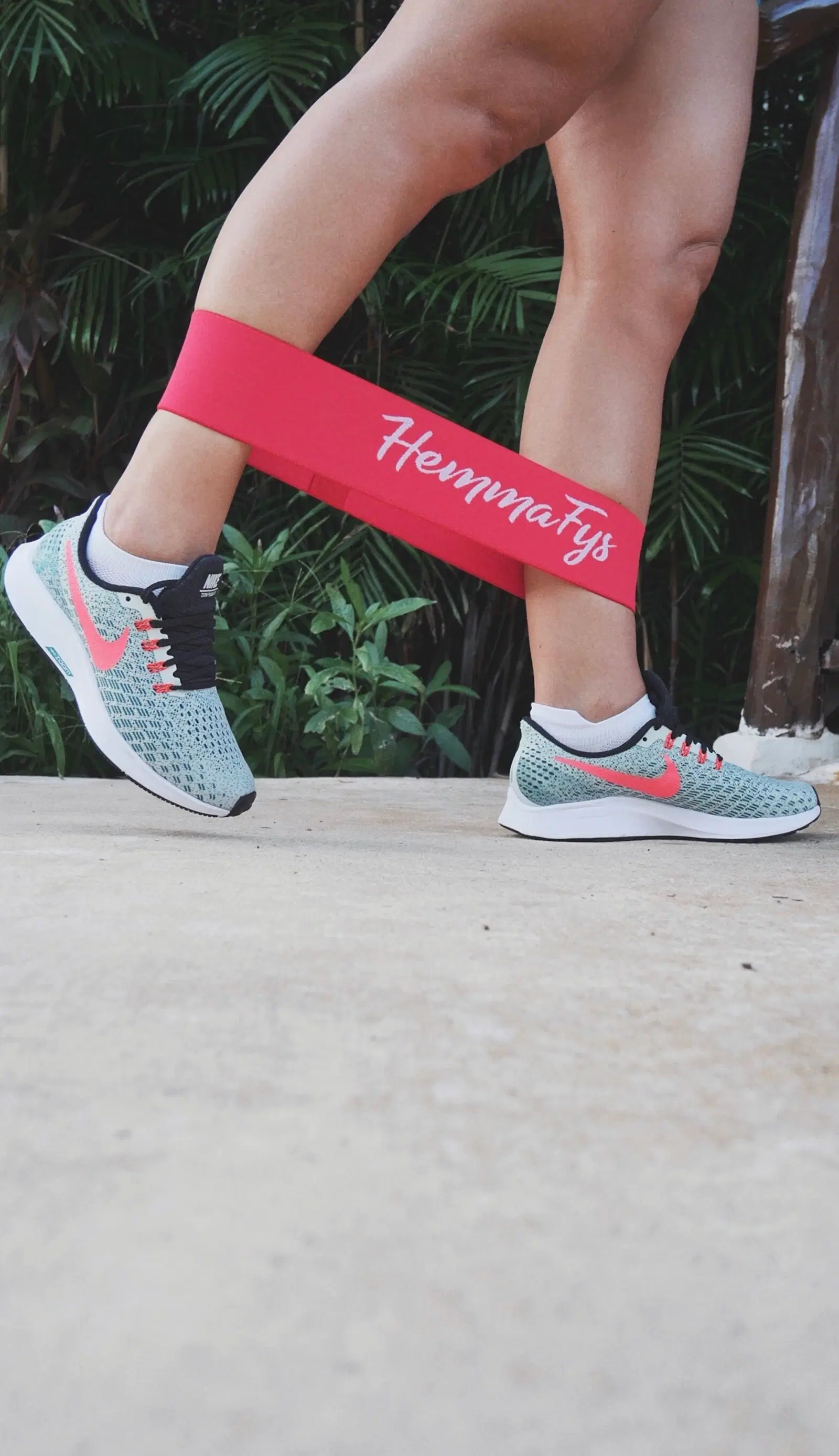 Red fabric resistance band looped around the lower legs mid-step in a banded walk for the side glutes
