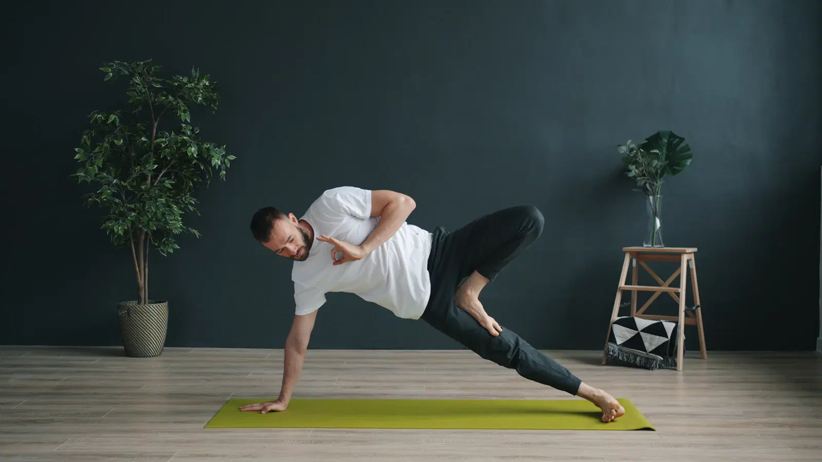 Man holding a side plank variation on a yoga mat to work the obliques at bodyweight