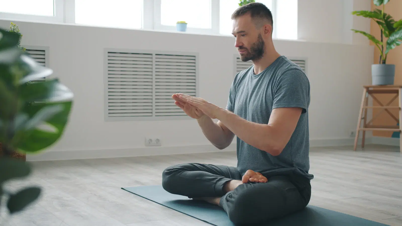 Man sitting cross-legged on a yoga mat, practicing the slow breathing used in stomach vacuums
