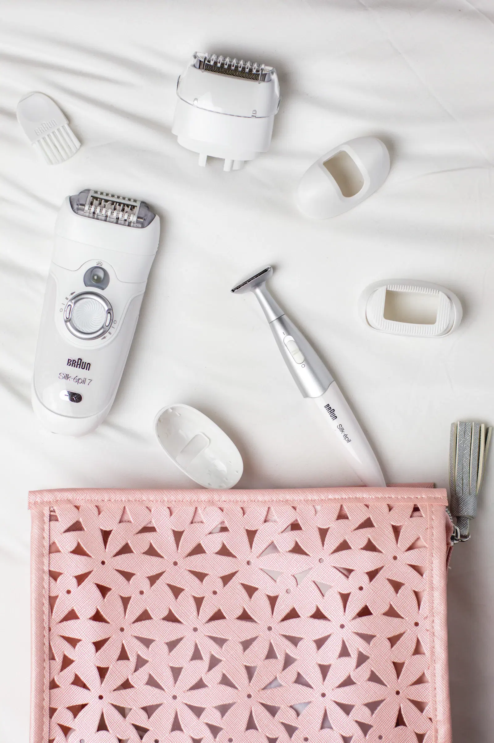 Braun Silk-épil epilator with its spare heads and a small trimmer laid out on a white sheet