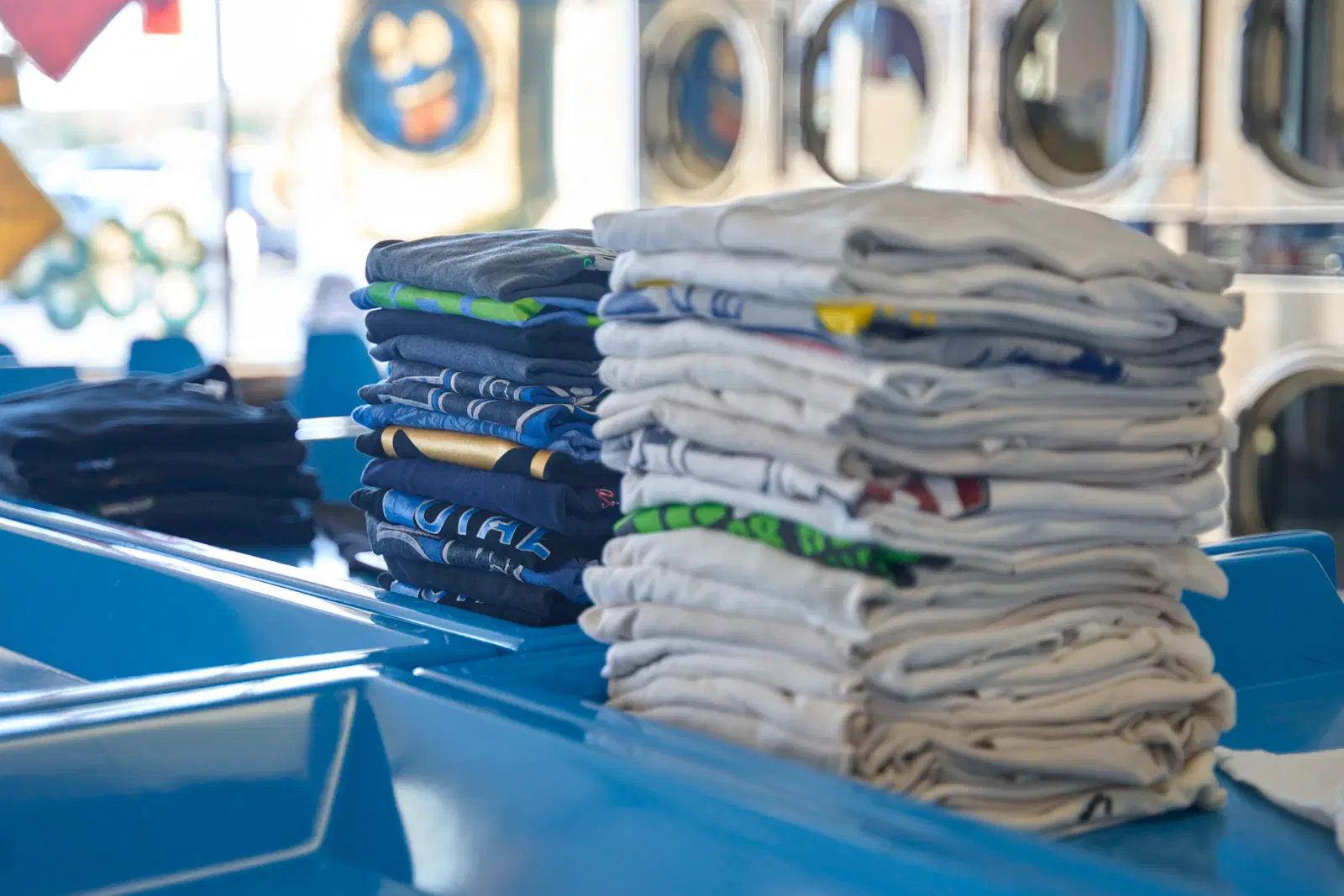 Stacks of folded cotton T-shirts at a laundromat, a breathable fabric that cuts inner-thigh friction