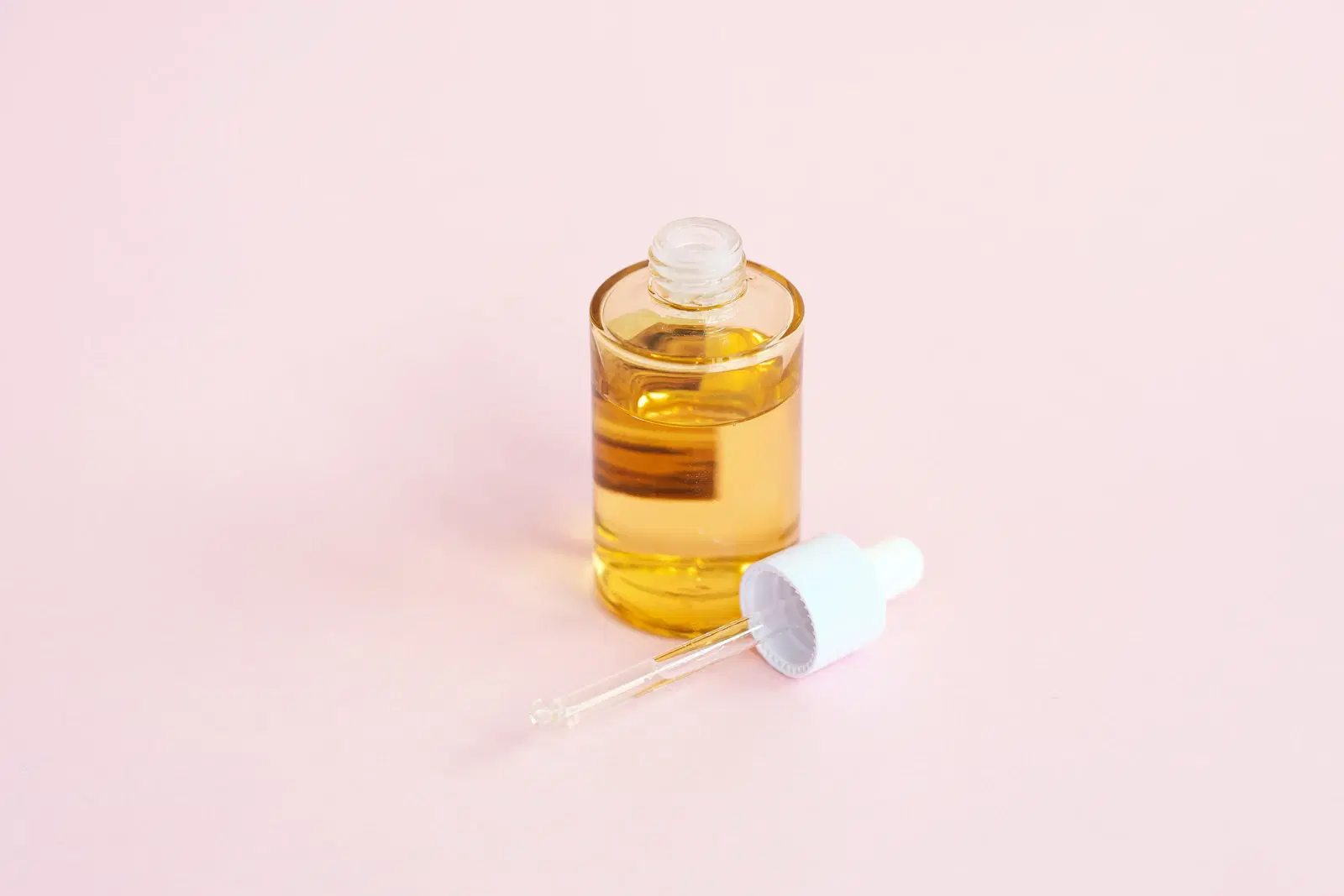 Serum bottle and dropper on a pink surface, a common way to fade dark marks left by ingrown hairs