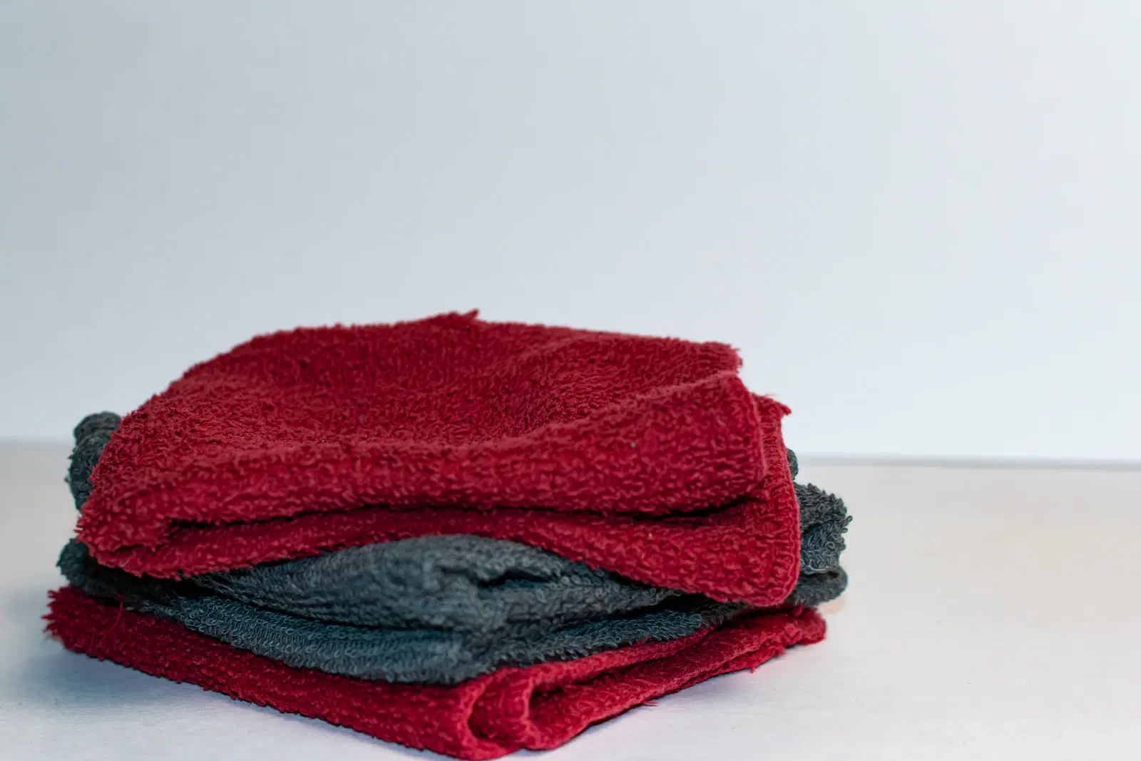 Stack of folded red and gray washcloths ready to use as a warm compress on an ingrown hair