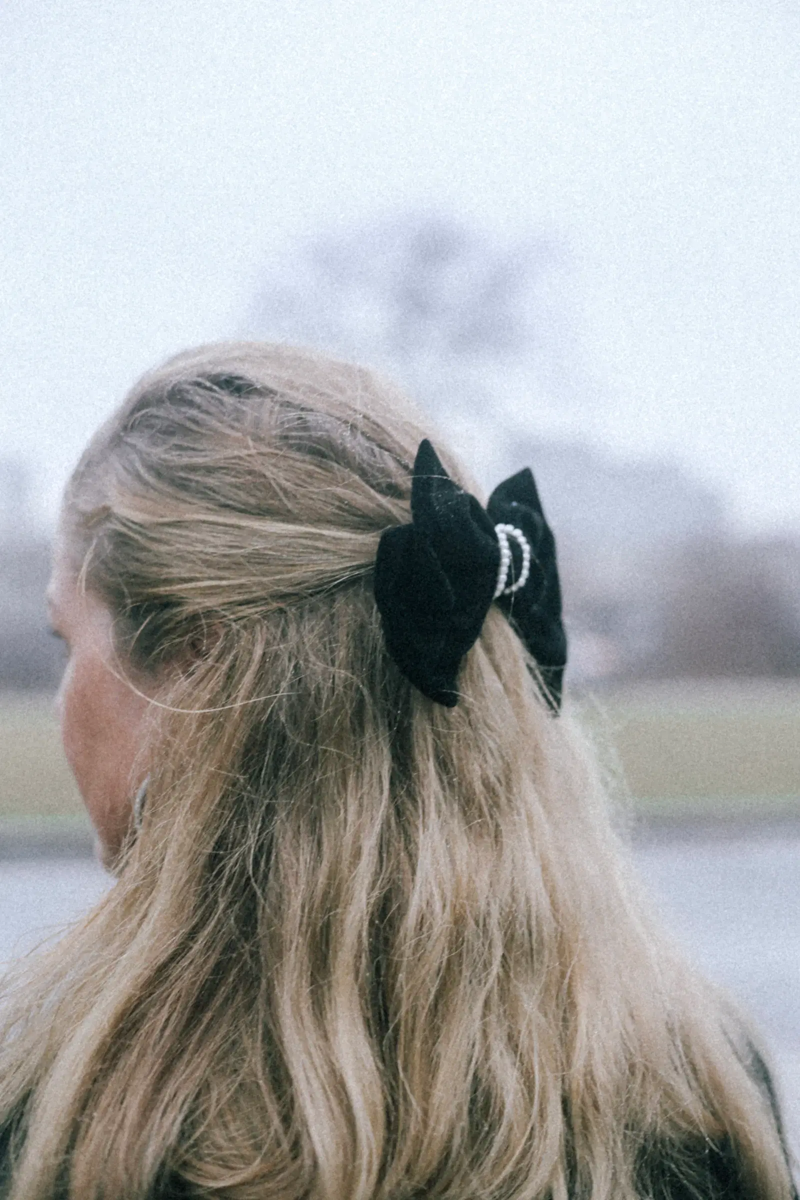 A large black velvet bow clipped into long blonde hair