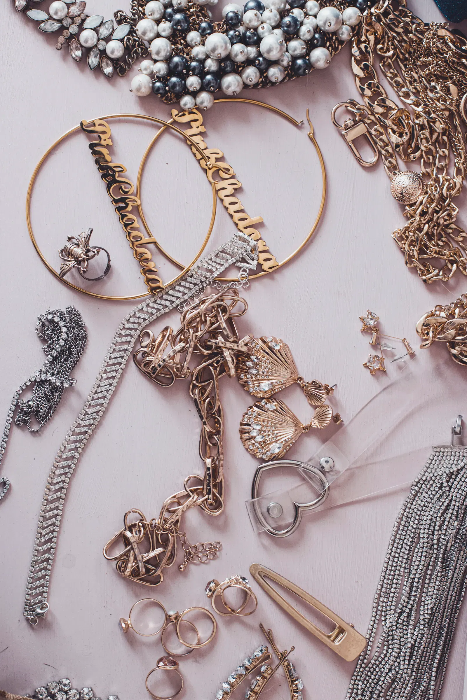 A pile of silver and gold necklaces, hoop earrings, rings, and hair clips