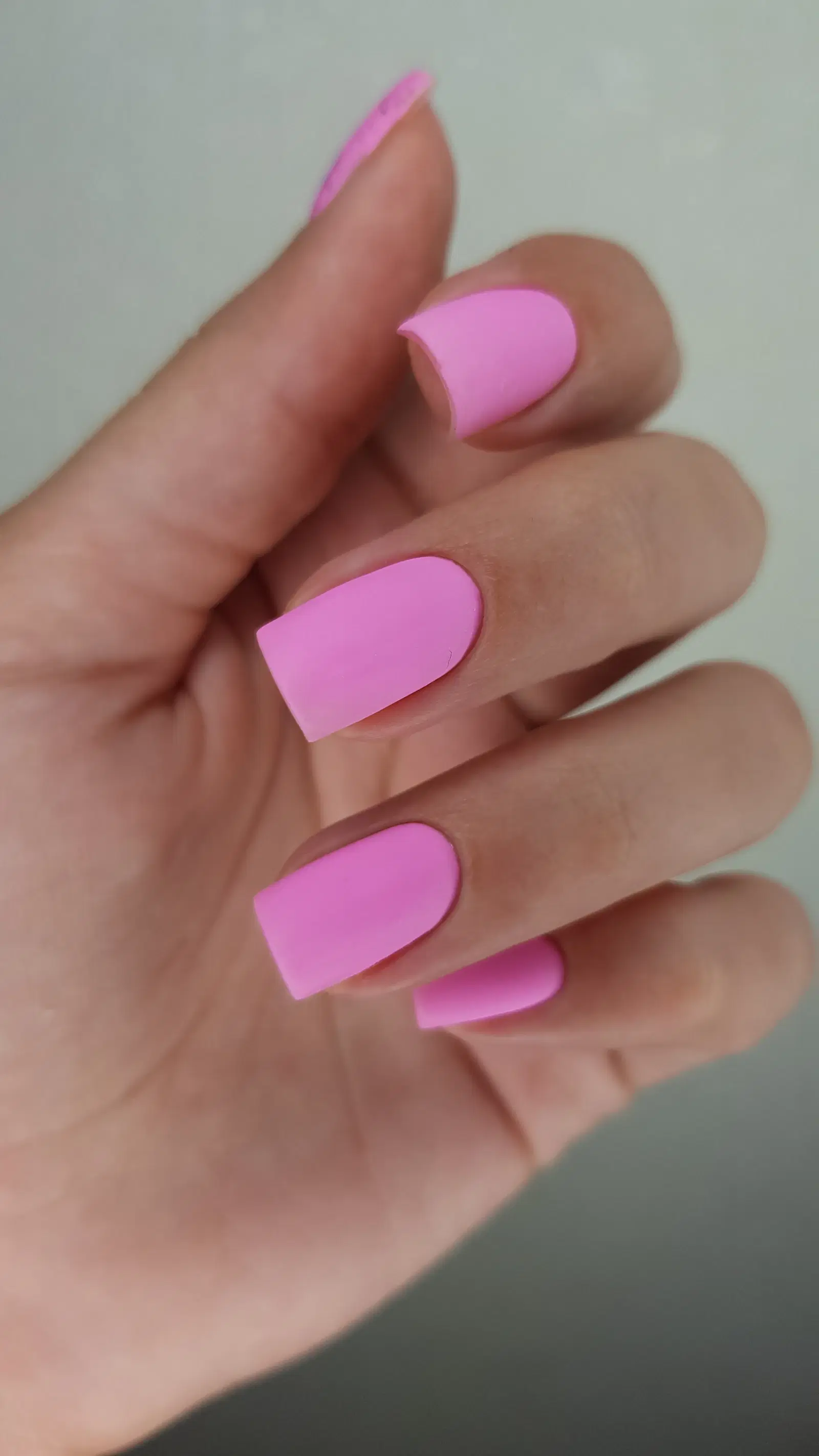 A hand with short, matte pink square nails